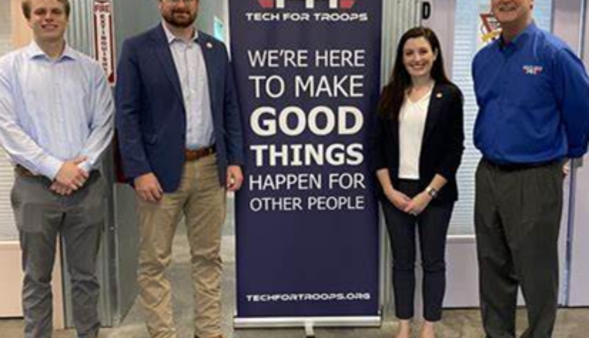 People standing with sign for Tech for Troops Nonprofit