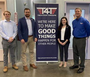 People standing with sign for Tech for Troops Nonprofit