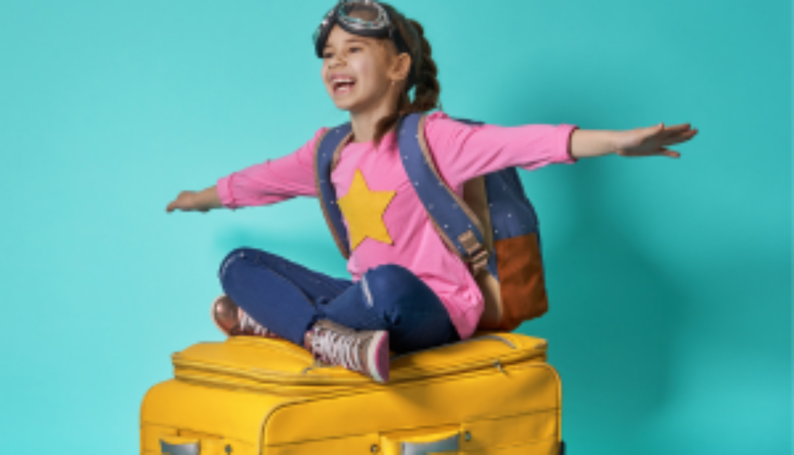 Girl sitting on suitcase with arms out, pretending to fly