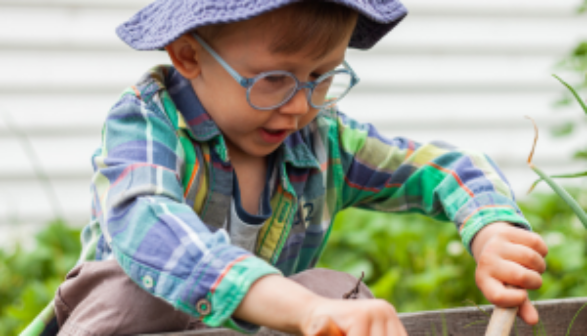 Child wearing a hat and glasses, planting a vegetable garden