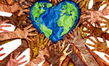 Heart-shaped paper Earth surrounded by paper hands made with many different skin tone colors.