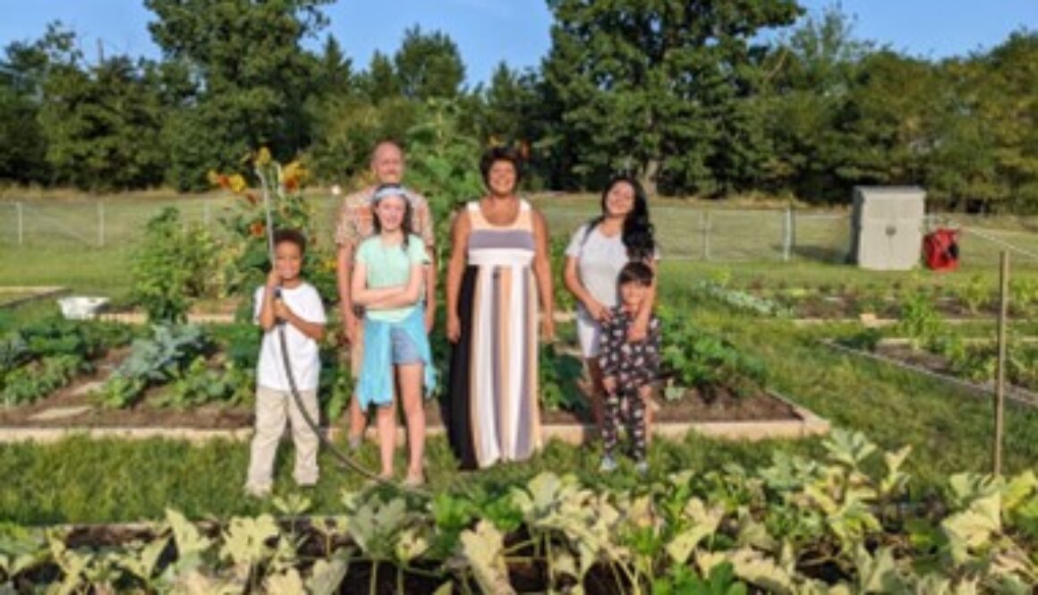 Photograph of people in a garden area with vegetables growing.