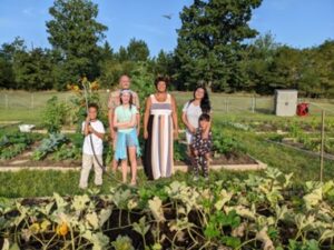 Photograph of people in a garden area with vegetables growing.