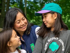 Lady and two girls, one with a Junior Girl Scouts t-shirt and ball cap