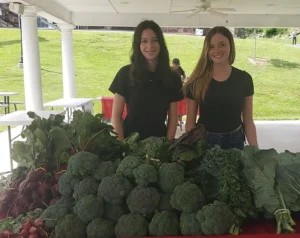 Young ladies with fresh produce at the Highland Center Pavilion Farmers Market