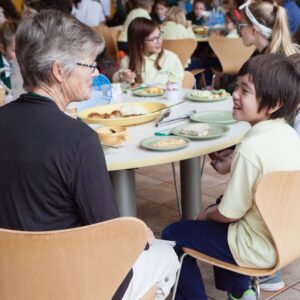 Students and an adult eating lunch at a school dining hall.