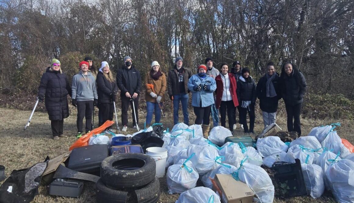 Volunteers standing with bags of litter that they cleaned up from a local park.