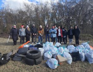 Volunteers standing with bags of litter that they cleaned up from a local park.