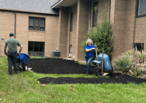 Volunteers adding soil from wheelbarrows to create a new vegetable garden.