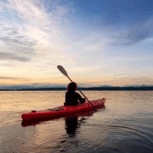 Person paddling a kayak in the water at sunset