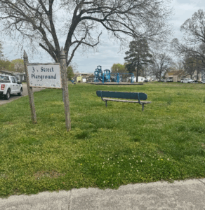Photo of park with old sign and worn bench