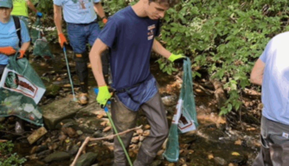 People wading in a creek tp pick up litter
