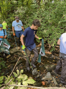 People wading in a creek tp pick up litter
